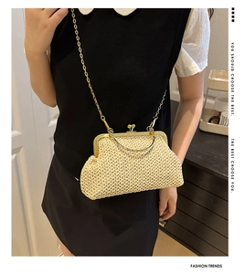 Detail of straw woven shell bag with gold clasp and metal chain on model