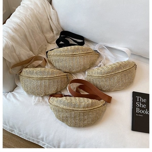Detail of four woven straw fanny packs with colorful fabric straps on a soft white sofa