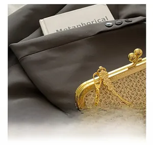 Detailed shot of beige straw handbag featuring golden floral engraved clasp and chain strap