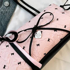 Detail of pink crinkle textured bag with black bow and silver heart pendant charm