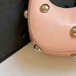 Primer plano de bolso de cuero rosa con grandes remaches esféricos plateados y textura suave