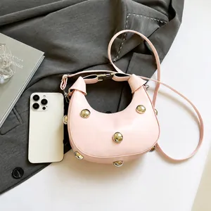Detalle de bolso media luna rosa con tachuelas plateadas sobre blazer gris