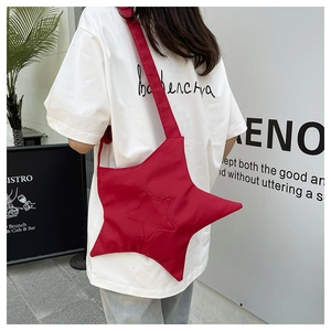 Red star-shaped canvas crossbody bag with wide shoulder strap shown on a model