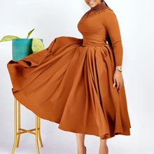 Detail of beaded embroidery on the turtleneck and pleated hem of this caramel dress