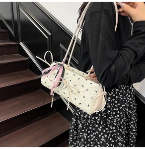 Close-up of cream shoulder bag featuring black bow prints and 3D ribbon decorations