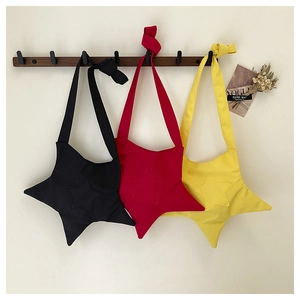 Three vibrant star-shaped crossbody bags in black, red, and yellow on wooden hooks