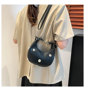 Vista laterale della borsa hobo nera con grandi borchie in metallo argento e tracolla