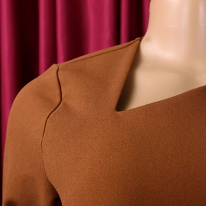 Detailed macro shot of caramel brown knit fabric texture and clean neckline stitching