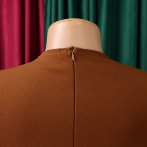 Detail of elegant caramel dress featuring a high waist and hidden zipper on the back