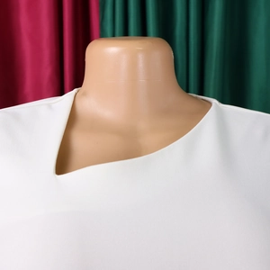 Detailed view of the elegant asymmetrical neckline on this white midi dress