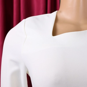 Detail of white asymmetric neckline and shoulder seam on a high waist elegant dress