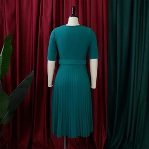 Detail view of the pleated hem and waist belt on a dark teal midi dress from the back