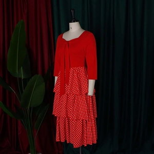 Detail of red tiered polka dot dress featuring a bow neckline and layered ruffle skirt