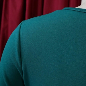 Detail of teal crepe fabric texture with round neckline stitching and pleated design