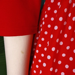 Detailed close-up of red and white polka dot fabric with soft sleeve cuff texture