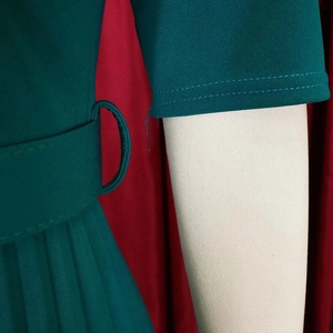 Macro detail of dark green pleated dress fabric with belt loop and woven texture