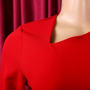 Detailed close-up of the V-neckline and stitched shoulder seams of a red elegant dress
