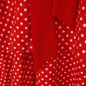 Detailed macro shot of red polka dot dress fabric with a large decorative matching waist tie