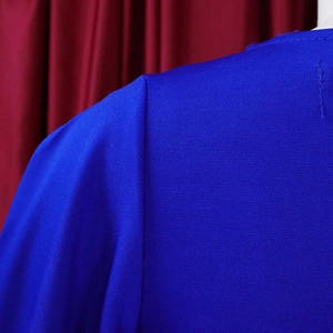 Close-up of royal blue knitted fabric showing shoulder stitching and sleeve seam detail