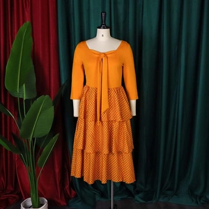 Detail of orange midi dress with bow neckline and tiered white polka dot skirt