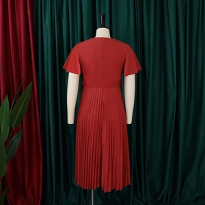 Detail of red pleated midi dress featuring a cinched waist belt and elegant flowing skirt