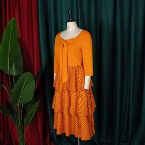 Detailed view of layered polka dot skirt with long sleeves and orange bow neckline