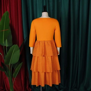Detail view of the back of a vintage orange dress with polka dot layered tiered skirt