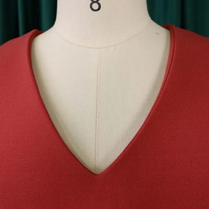 Detail of the V-neckline on the deep red pleated dress with high-density fabric