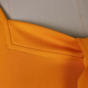 Detail of orange mesh fabric with neat stitching and breathable knit texture on dress