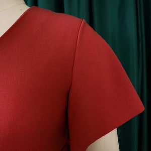Detailed view of red V-neck dress featuring short sleeves and textured fabric