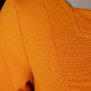Close-up of orange dress featuring high-quality square neckline stitching and fabric texture