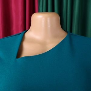 Detail view of teal dress with an elegant asymmetric neckline and premium fabric texture
