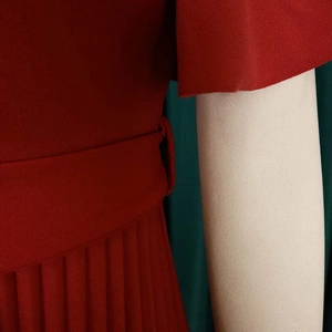 Close-up of red V-neck dress showing pleated skirt detail and matching waist belt