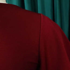 Close-up of high-quality sewing stitches and knit texture on burgundy dress sleeve