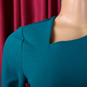 Detail of teal midi dress featuring a sharp notched V-neckline and elegant shoulder seam
