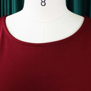 Detailed close-up of dark red round neckline with fine knit texture and double stitching