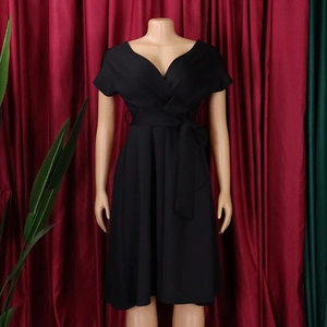 Detail of a black V-neck A-line dress with a belted waist bow shown on a mannequin