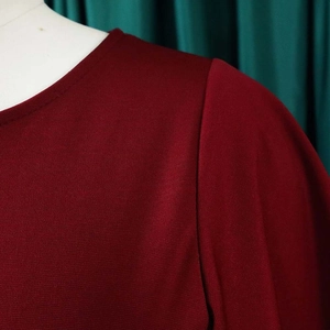 Detail of round neckline and knit texture on this burgundy office dress with flared sleeves