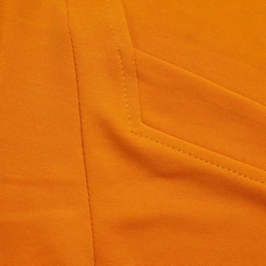 Close-up of double stitching on orange knit fabric showing high-quality garment detail
