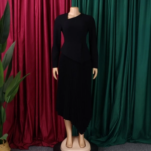 Close-up of black long-sleeve dress with asymmetrical neck and pleated hemline detail