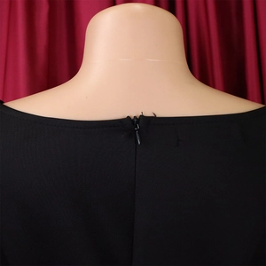 Detail of invisible back zipper closure on elegant black deep V-neck evening dress