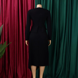 Detail of black long sleeve midi dress featuring peplum waist and irregular pleated hem