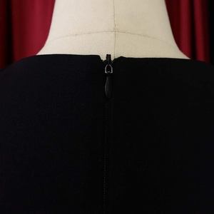 Close-up of the high-quality invisible zipper closure on the back of a black V-neck dress