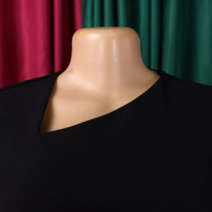 Detail view of the asymmetric slanted neckline on this elegant black high-waisted dress