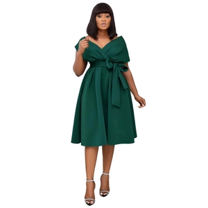 Detail of dark green off-shoulder dress with decorative bow tie and pleated skirt