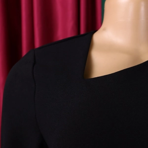 Detail of elegant black dress showing V-neckline and shoulder tailoring on mannequin