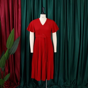 Detail of red V-neck dress featuring ruffled sleeves and a pleated skirt with belt