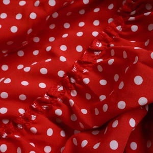 Detail of red fabric with white polka dots featuring layered ruffle textures
