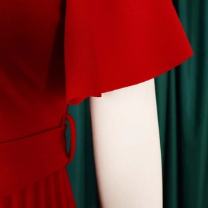 Detail of red V-neck dress with pleated ruffle sleeves and matching fabric belt buckle