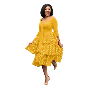 Detail of yellow long sleeve dress featuring polka dot tiered skirt and waist tie accent